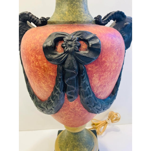 This cast plaster lamp has a faux stone finish. There is a terracotta red and pea soup green accented with swags and goat...