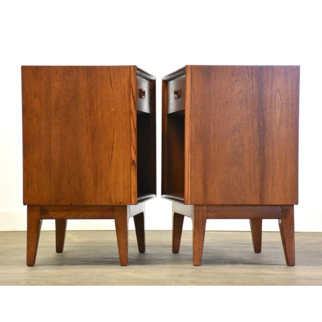 A pair of mid century modern teak nightstands with a single drawer and a lower shelf. Professionally refinished. 22” wide....