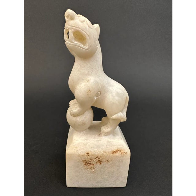 A Jade Foo dog, its front paws mounted on a ball, its mouth held open in a snarl. A Foo dog, in Chinese culture, is a...