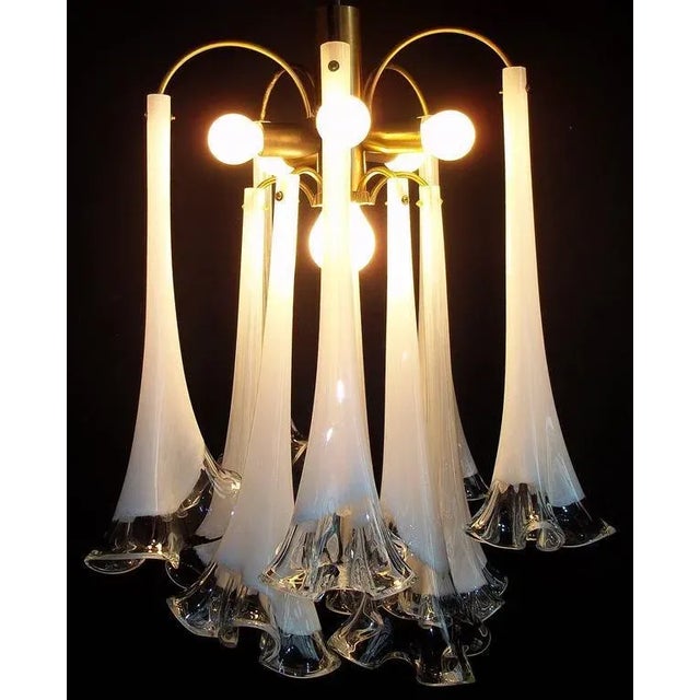 The chandelier is made of a brass structure from which hang nine beautiful flowers Murano glass illuminated from five...
