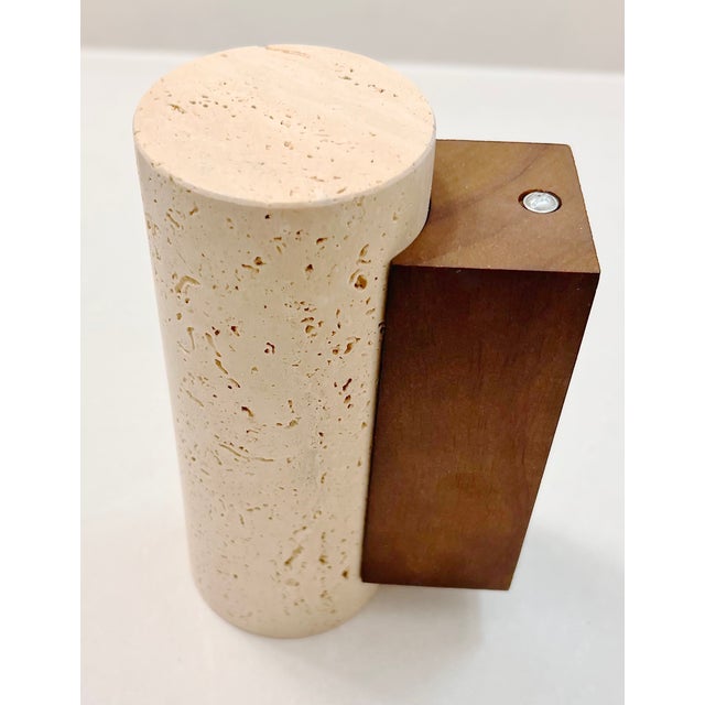 Minimalist wall sconce featuring a solid travertine stone cylinder paired with a warm wood backplate. This compact 6.4″...