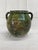 A substantial hand-thrown earthenware jar with a luminous green glaze applied over a pale slip, revealing soft white...