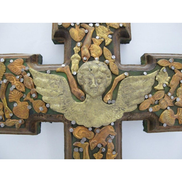 Wonderful Mexican folk art Milagros hand carved wood cross. The surface is densely covered with small, stamped brass and...