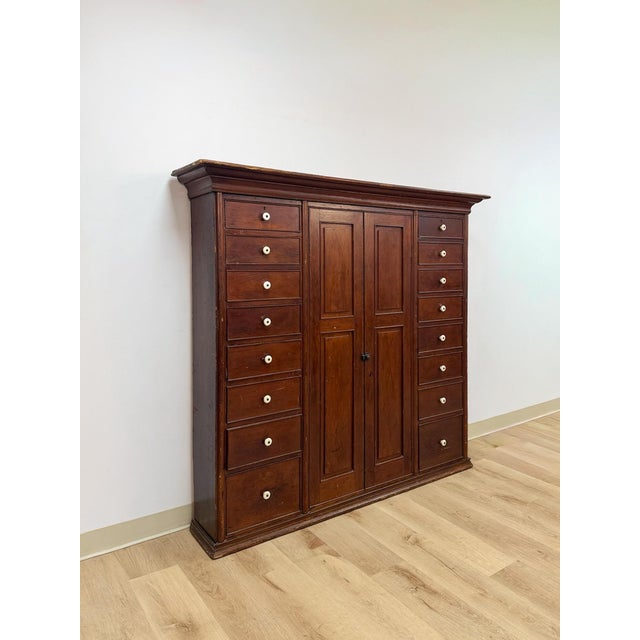 This exceptional large antique apothecary cabinet with sixteen drawers and two doors is a genuinely rare and commanding...