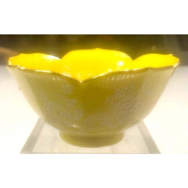 This beautiful hand decorated yellow bowl in the shape of a lotus flower has raised white floral artwork on its inner and...