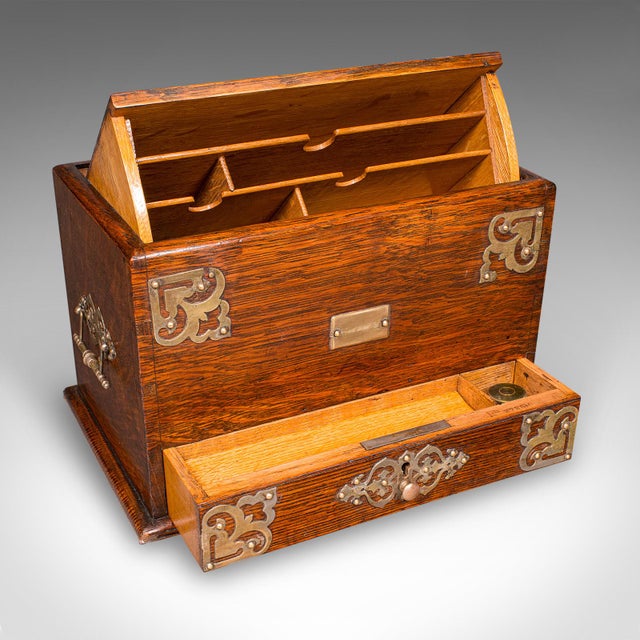 This is an antique metamorphic stationery case. An English, oak and brass writing box, dating to the Edwardian period,...