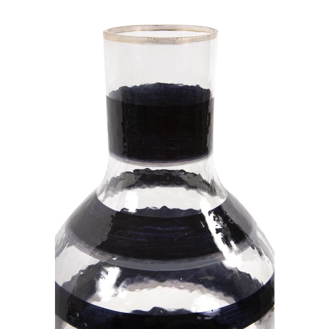 The Vector glass bottle vase features a hand painted black swirl pattern and a simple gold touch on the rim to complete...