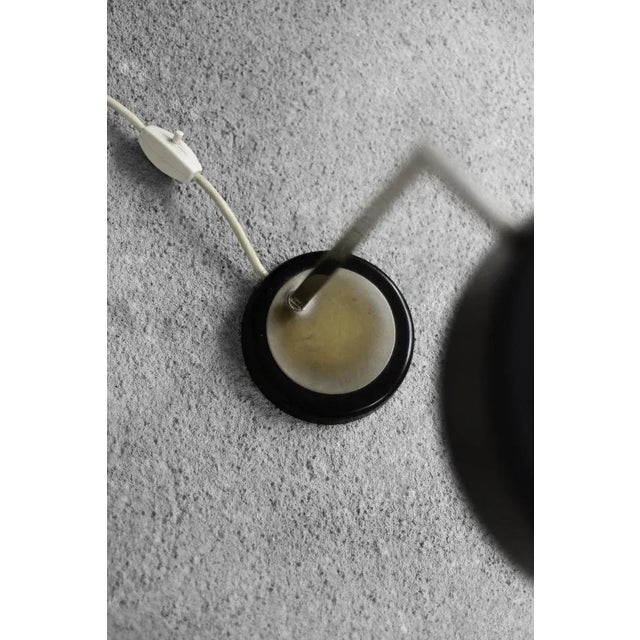 This minimalist lamp was produced in Germany during the 1960s. The lamp captivates with its simple design. The black metal...