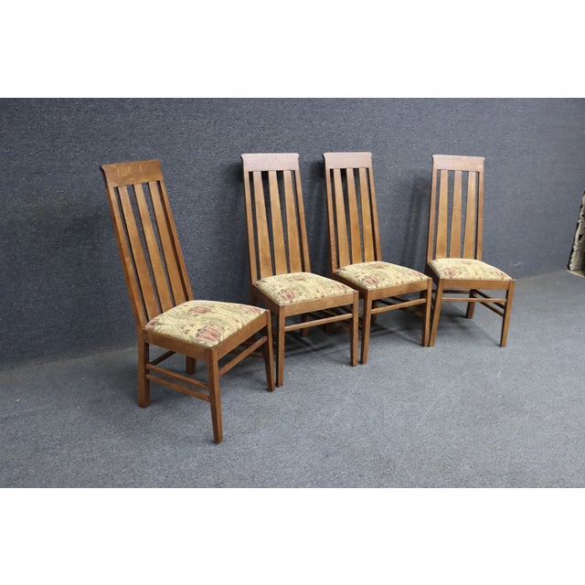 Set of four Mission Oak dining chairs by L. & J.G. Stickley. Made of solid oak with tall slat backs and upholstered seats....