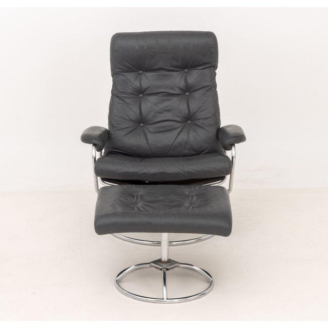 Ekornes Gray Leather Upholstered Lounge Chair and Ottoman, with chrome-plated circular bases. 37" H x 30" W x 26" D; seat:...