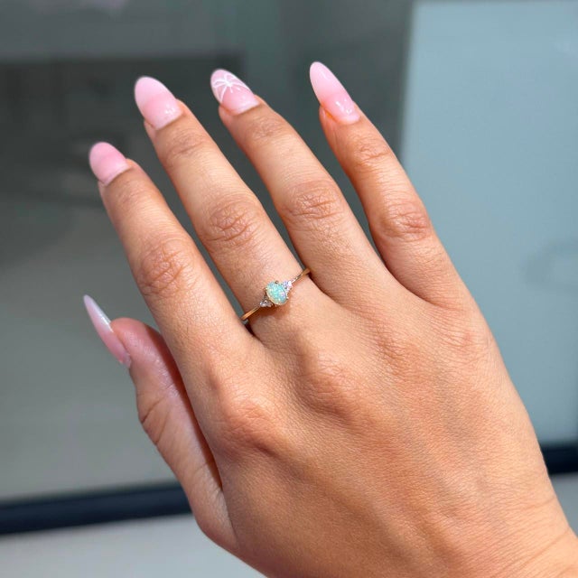 This elegant ring showcases a 0.35 carat natural oval cabochon opal, set in 14k yellow gold. The center stone measuring...