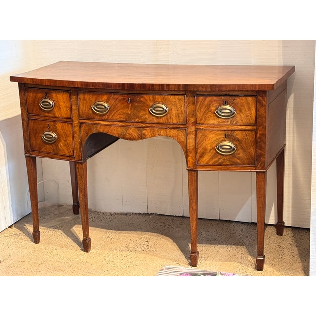 Regency period mahogany sideboard with a bowfront form and richly figured veneer. The central drawer is flanked by banks...
