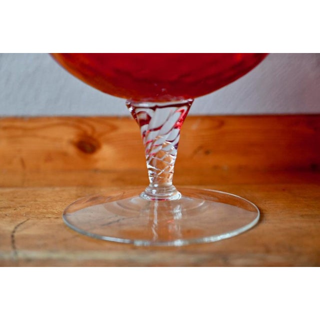This large grenadine red glass bowl with a serrated rim and twisted foot was made in a glassworks in Empoli, Italy in the...