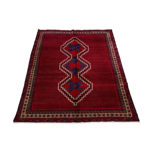 Vintage Shiraz wool rug has a red field and blue accents in a center tribal motif. This rug measure 6'5" x 9'5".
