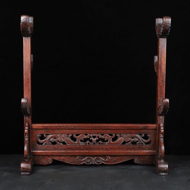 A beautifully crafted Chinese display stand, likely made of Huali (rosewood). The piece is designed to hold a sword,...