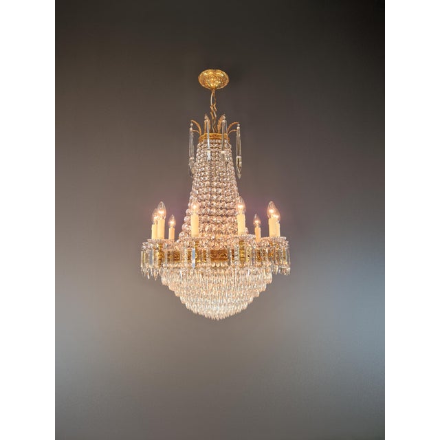 A antique crystal chandelier in the style of the French Empire Revival, dating from around 1920. Its imposing height,...