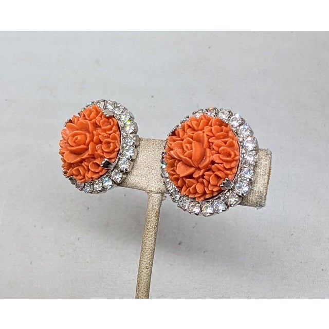 1950s rhodium plated round carved faux-coral center with round clear rhinestone surround clip earrings. Marked "KRAMER NEW...