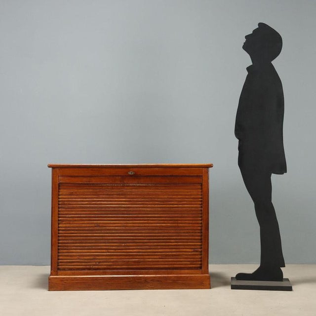 Oak storage cabinet of Italian manufacture from the 1950s-60s, featuring a front tambour door that reveals a practical...
