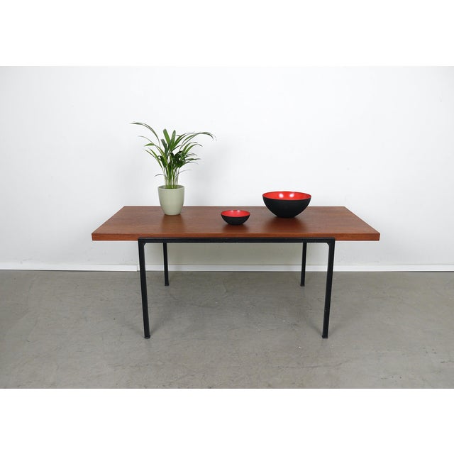 Rectangular coffee table with teak top and offset black painted square metal frame from the 1960s. The coffee table was...