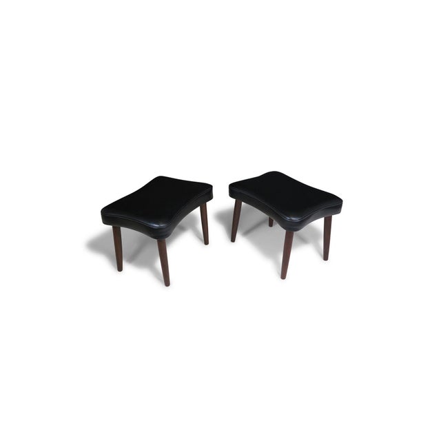 Pair of Danish ottomans upholstered in the original black vinyl, raised on round tapered legs. (Unmarked) Measurements W...