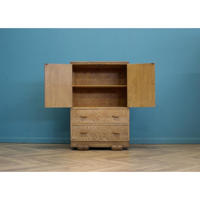 1930s Art Deco limed oak tallboy cabinet with beautifully figured grain throughout. The upper double-door cupboard...