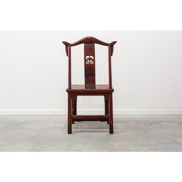 Chinese dining room chair made in solid wood skied completely in reddish tone with decoration in gold in backrest and skirt.
