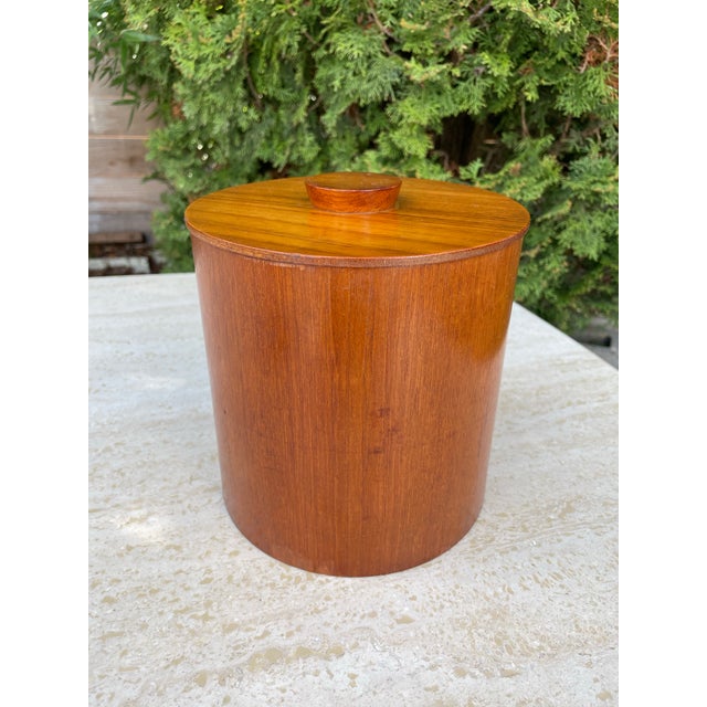 A vintage Danish Modern teak canister crafted of richly grained teak wood in a cylinder shape.