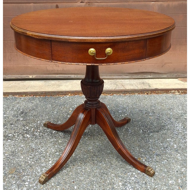 A 1940s Georgian-style Mahogany Drum Table with a Single Drawer and Brass Hardware on a pedestal quadpod Pedestal....