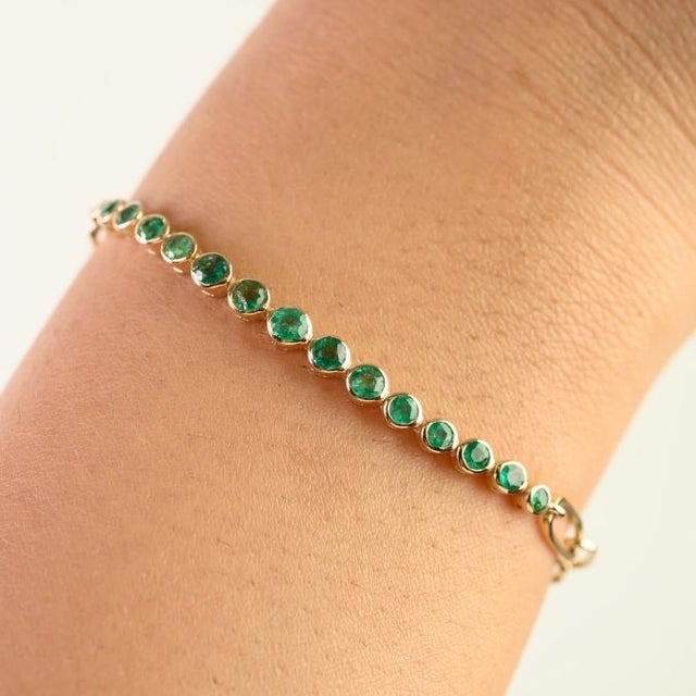 This elegant station chain bracelet features 15 round cut emeralds totaling 0.85 carats, set in 14k yellow gold. Each...