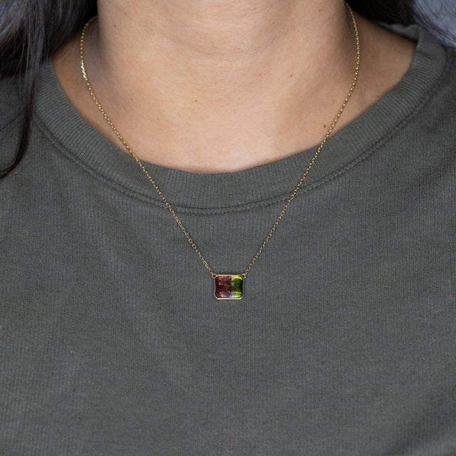 A 5.48-carat bi-color tourmaline blends natural red and green in a single rectangular stone, bezel-set in solid 14K yellow...