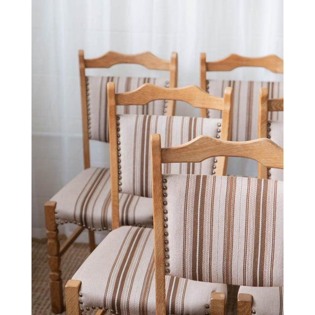 A set of six 1970s Danish oak dining chairs in the style of Henning Kjærnulf, showcasing the warm, rustic elegance of...