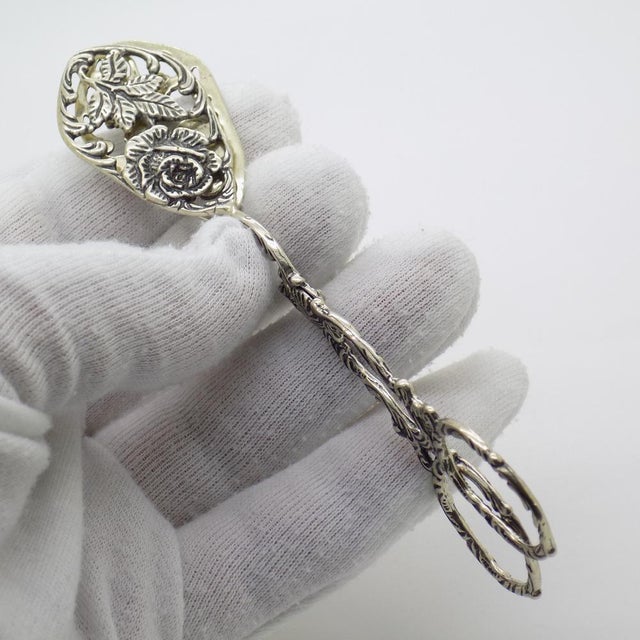 A pair of small vintage sugar cube tongs, handcrafted in 800/000 silver in Italy between the 1970s and 1980s, reflecting...