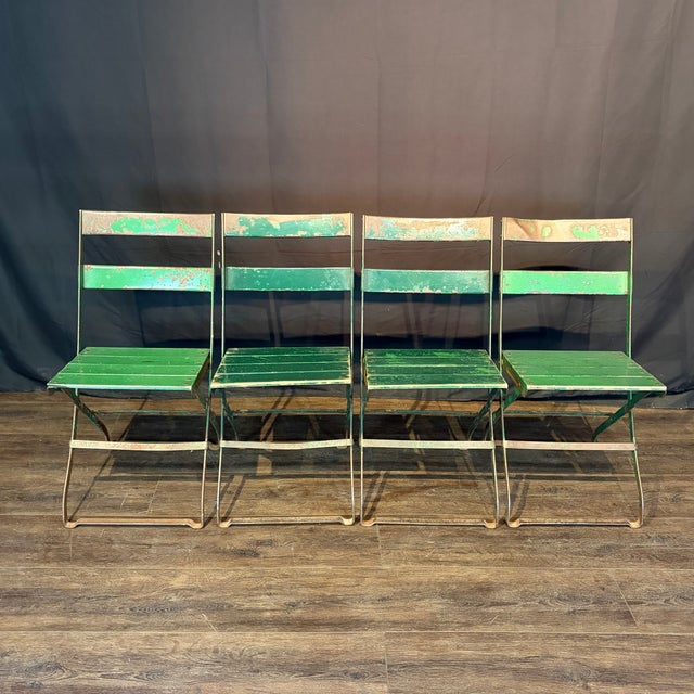 Antique French folding chairs from the 1920s: feature slatted green painted wood and metal frames. Great chair set indoors...