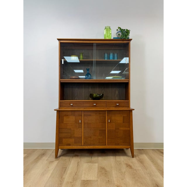 This vintage hutch by Paine Furniture showcases a rich red-toned wood finish paired with striking parquet door detailing,...