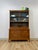This vintage hutch by Paine Furniture showcases a rich red-toned wood finish paired with striking parquet door detailing,...