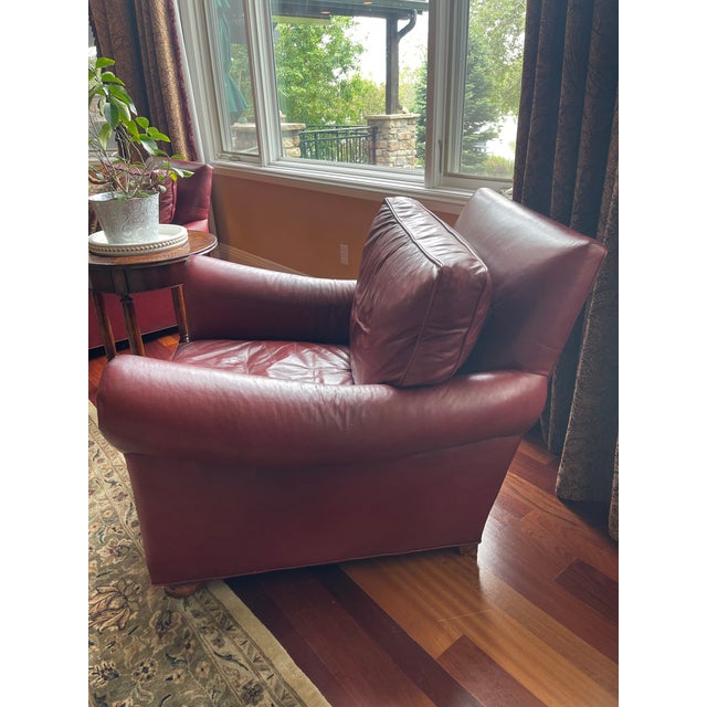 Late 20th Century made in USA. Substantial burgundy leather club chairs with brass nailhead trim, wooden bun feet and...