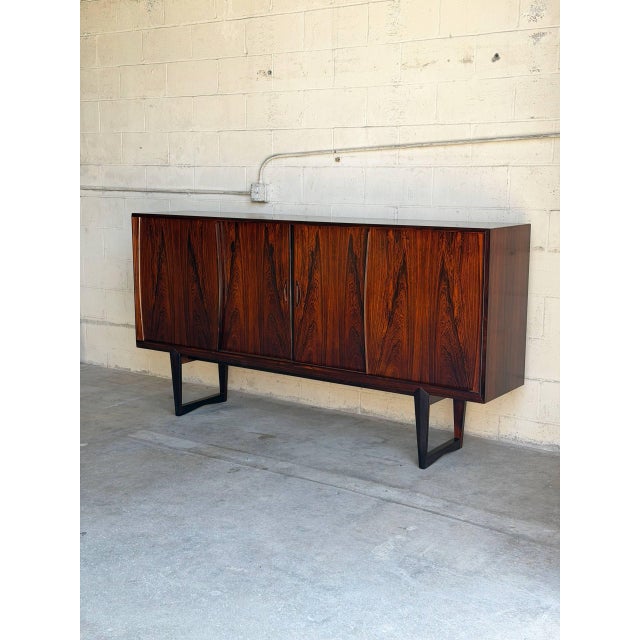 This architectural highboard features a long geometric chassis elevated by an iconic open sled base. Smooth sliding doors...
