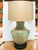 An elegant large table lamp consisting of a converted ceramic urn body in a celadon green glaze, an ebonized carved wooden...