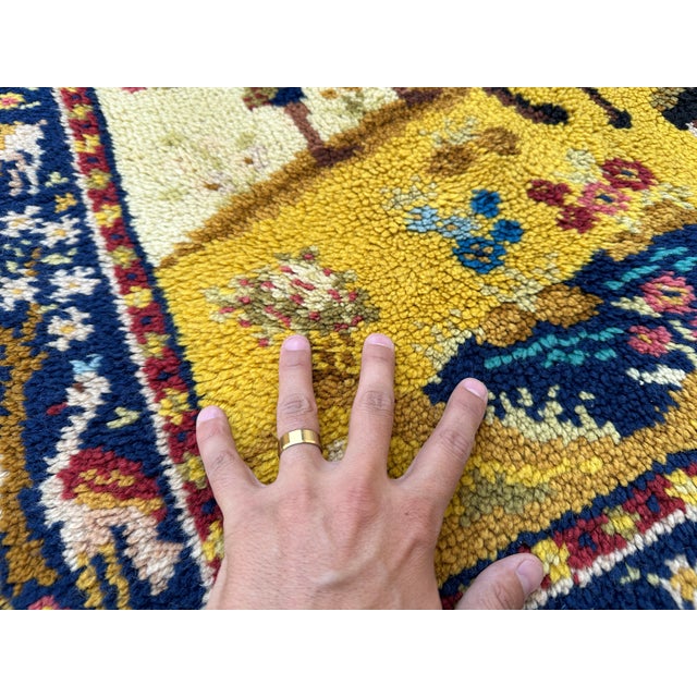 This hand-knotted wool rug presents a vivid pictorial composition of a royal procession, with mounted figures, a parasol...