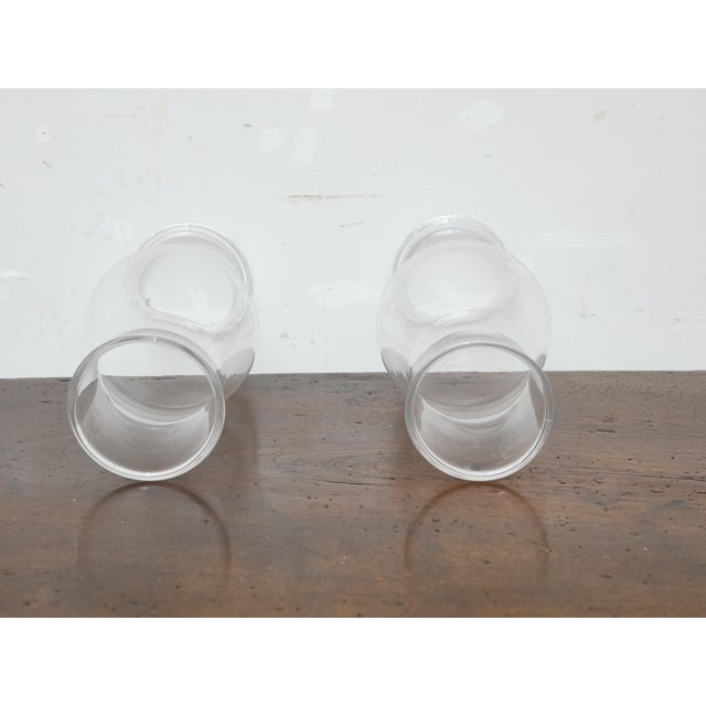 This handsome pair of tall hurricane glass shades dates to circa 1900 and was made in England. Handblown in clear glass,...