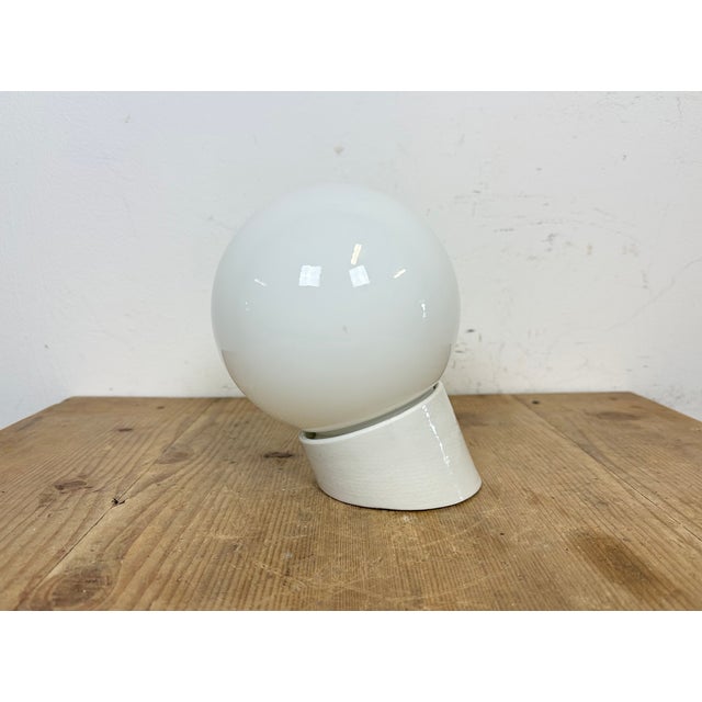 Vintage industrial light made in former Czechoslovakia the 1970s. It features a white porcelain wall mounting and a milk...