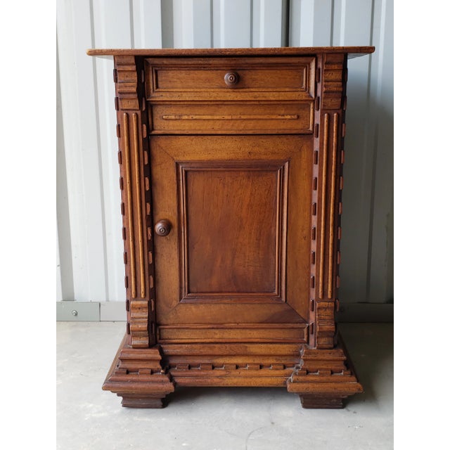 A highly carved antique French walnut bedside table. Handcrafted in the 19th century, having a rectangular wooden top,...