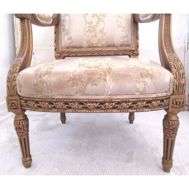 Antique French Louis Gilt Bergere Chair with ornate carvings and damask bows and roses fabric.