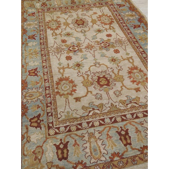 Stylized flowers on an ivory field within soft blue border. Wool pile on cotton foundation. 5'x 7'9".