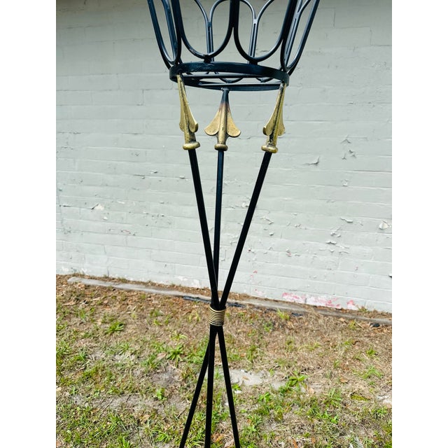 These are a striking pair of vintage wrought iron plant stands or torchères, designed with elegant classical motifs and a...