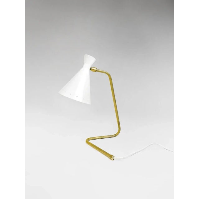 Elegant sculptural table lamp shown in un-lacquered natural brass with ivory shade fabricated in Italy by Fabio Ltd. This...