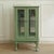 Small display cabinet refinished in pastel green with glass doors, a built-in glass shelf, and a mirrored interior back...