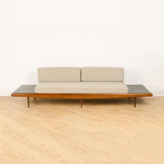 A Mid Century Modern sofa in the manner of Adrian Pearsall. Walnut with slate inlay end tables circa 1950s. Materials:...