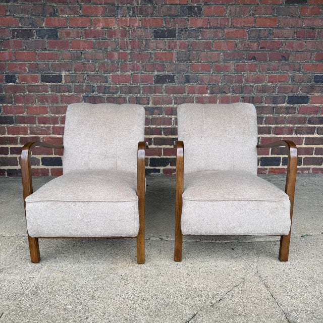 Beautiful pair of European modern lounge chairs newly refinished and professionally reupholstered. These chairs feature...