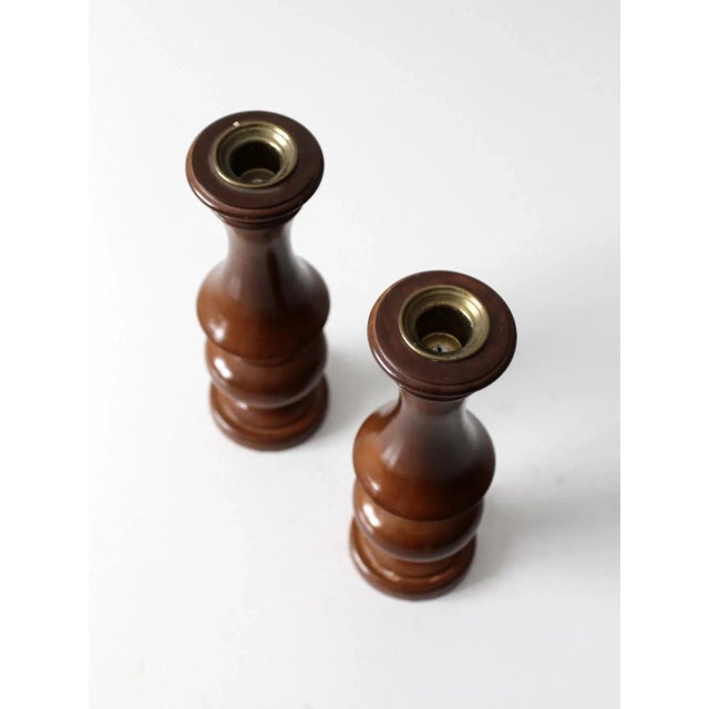 This pair of vintage wooden candleholders showcases a warm polished finish with sculptural turned forms and brass inset...